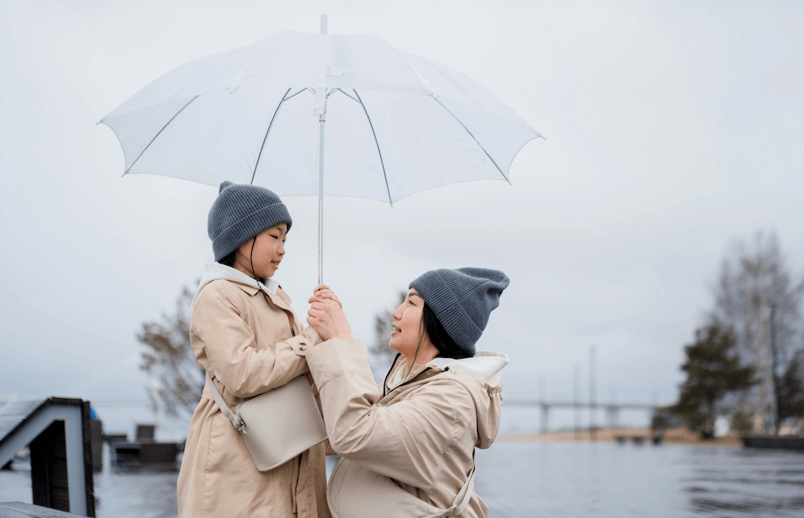 A mother and her daughters feeling safe under an umbrella