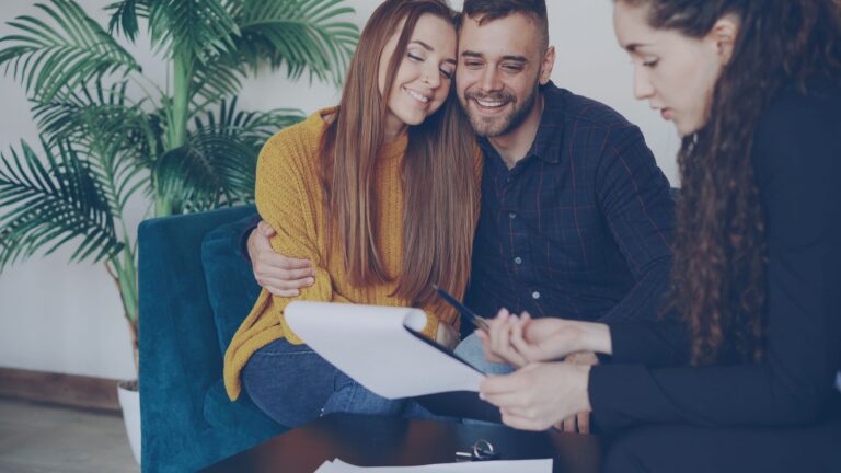 Self-employed couple reviewing a life insurance calculation with an advisor in a cozy office