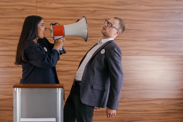 Two people in business attire argue face to face as one shouts through a megaphone, illustrating the noisy debate around Medicare Advantage changes in 2027.