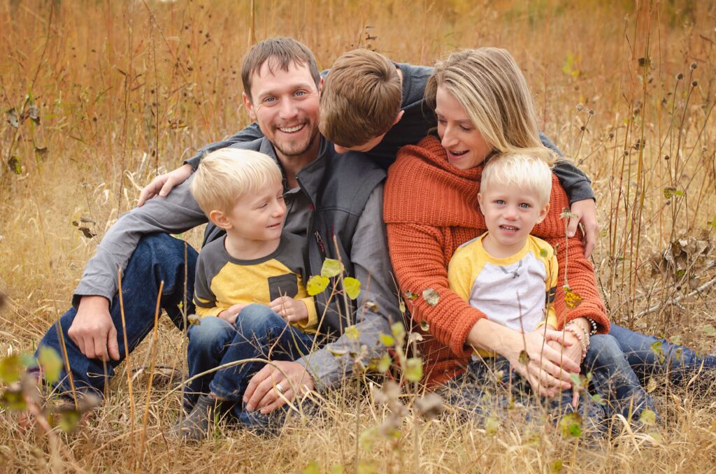 Family of five in yellow sweaters sitting together in an autumn field, the kind of family term life insurance is designed to protect