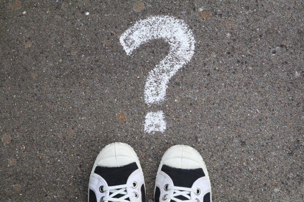 White sneakers on gray pavement beside a large chalk question mark, illustrating uncertainty about Utah health insurance rates for 2027