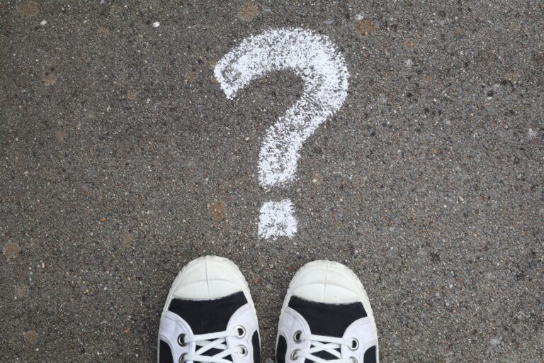 White sneakers on gray pavement beside a large chalk question mark, illustrating uncertainty about Utah health insurance rates for 2027
